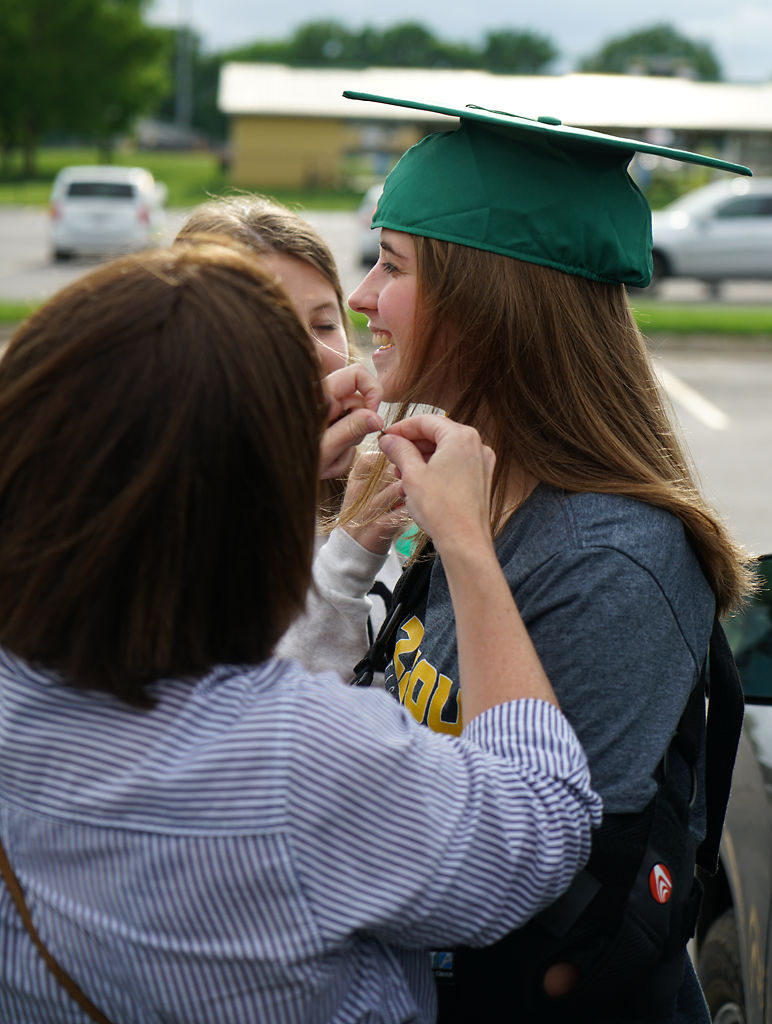 Amy Mackley helps her daughter, Samantha Mackley, with her graduation hat
